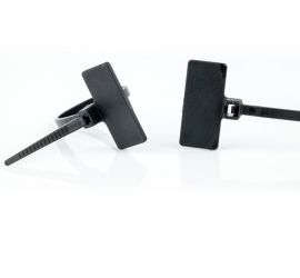 Technische tekening van verschillende typen kabelbinders met markeerlabel.;;Een zwarte kabelbinder met markeerlabel, met het label boven de kop van de kabelbinder, gebonden rond een blauwe kabel.;Twee zwarte kunststof kabelbinders met markeerlabel, met he